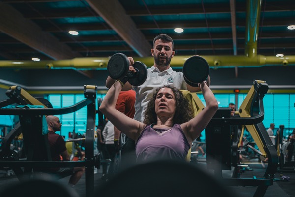 Jay coaching woman on military press.